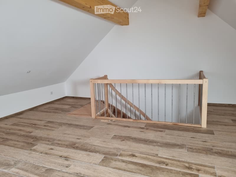 Wooden floor, white walls, wooden staircase, metal railings, light switches on the wall