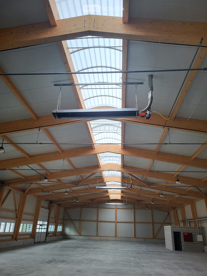 Warehouse interior with wooden beams, skylights, concrete floor, industrial lamps, walls and doors