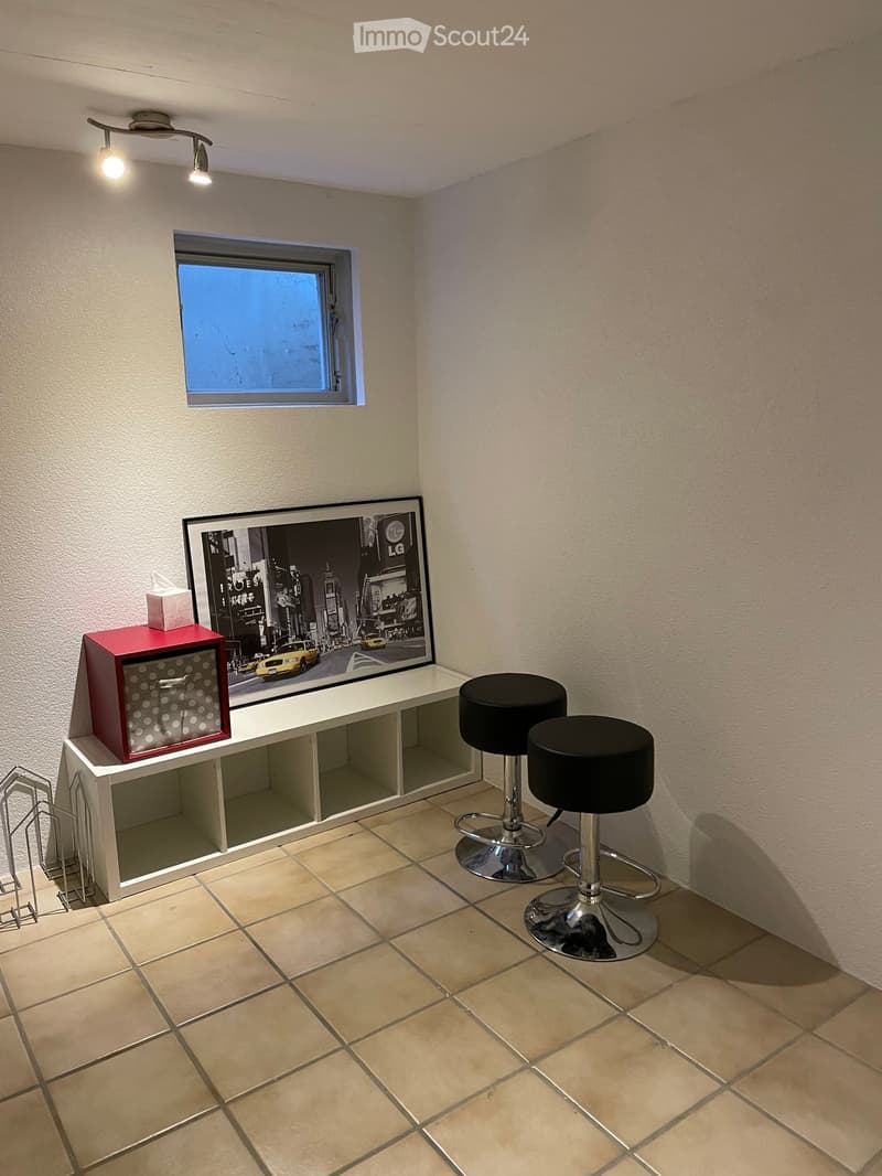a room with a shelf, stool, and framed photo
