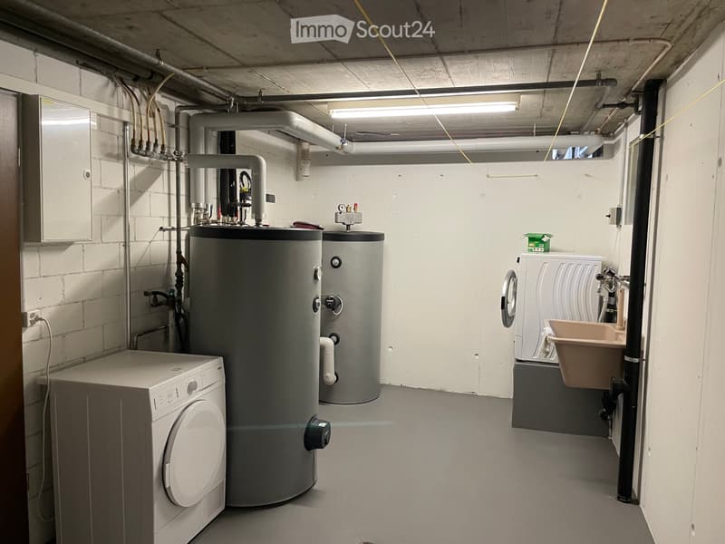 Utility room with two water heaters, white washer, and a beige sink.