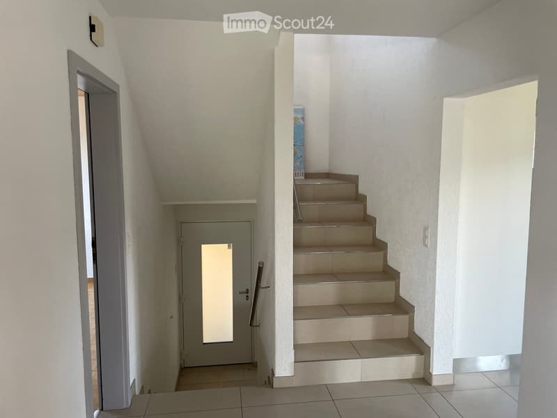 Entrance with door, open door, white tiled flooring, modern white wall, a staircase leading to upper floors