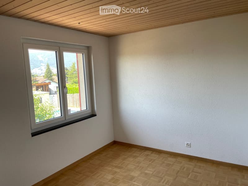 an empty room with large window and wooden floor