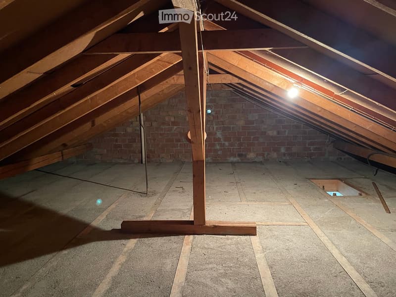 unfinished attic room with wooden beam, brick wall, hatch