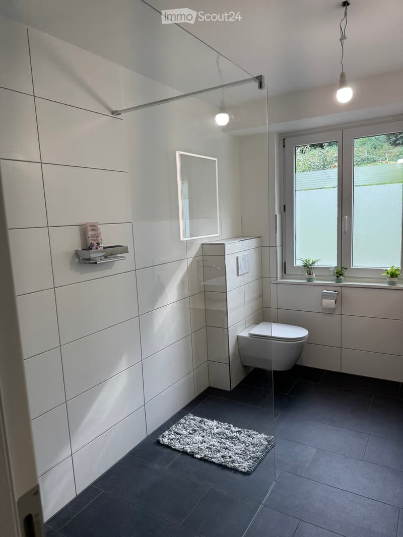 modern bathroom, white tiles, glass shower enclosure, white toilet, window, rug, white fixtures
