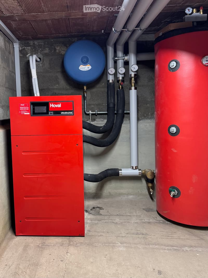 Red and blue appliances mounted on brick wall, connected by black and white pipes, steel floor