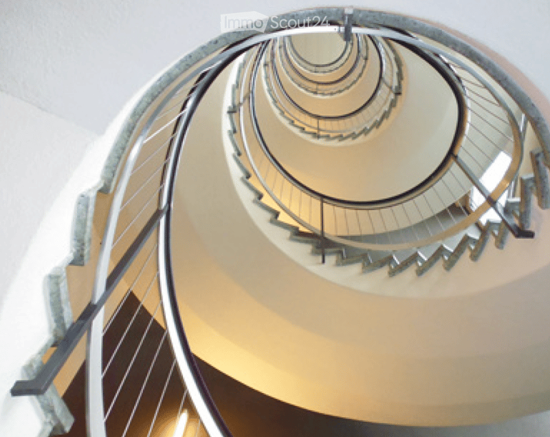 Spiral staircase with metal handrail, concrete steps, and glass wall