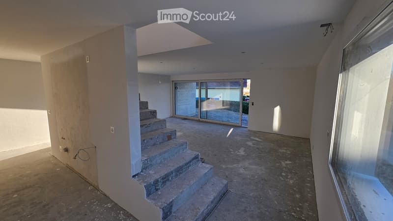 Empty room with concrete floor, concrete stairs, glass doors, and windows