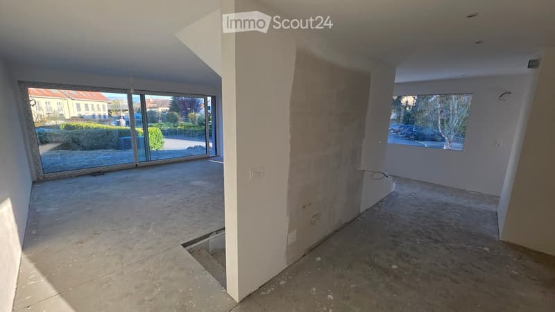 Empty room with concrete floor, large windows, unfinished walls, and electrical outlets