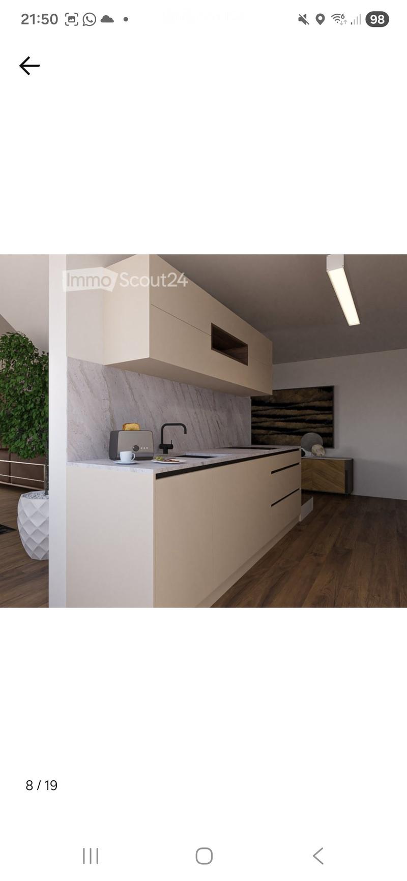 Modern kitchen with light-colored cabinets, marble backsplash, and wooden flooring. Includes a faucet, toaster, cup, and plate on the counter.