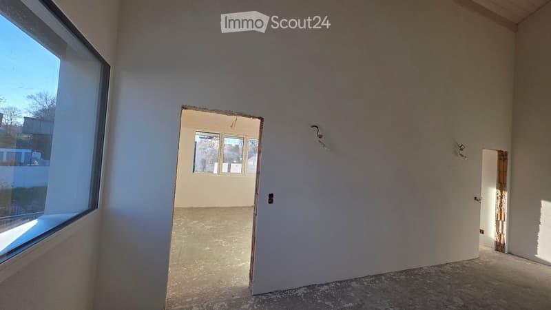 Empty room with white walls, concrete floor, large window, two doorways