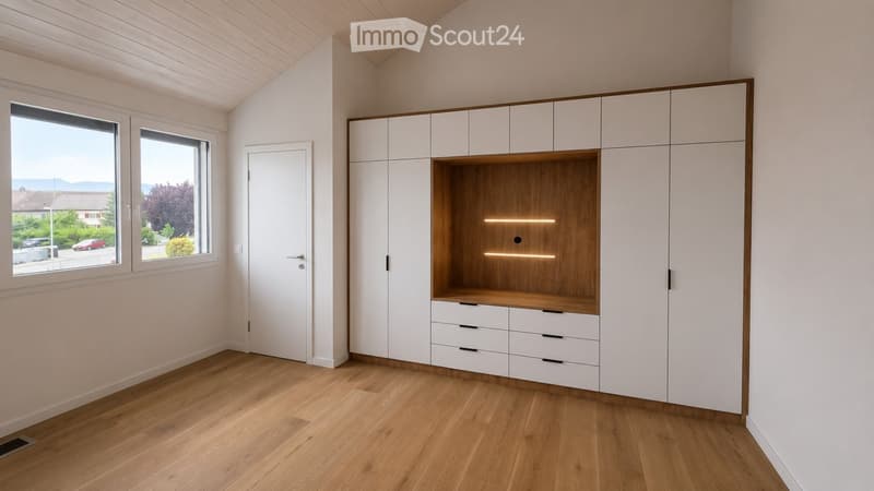 Empty room with light wooden flooring, white walls, large windows, and built-in white cabinetry with a wooden accent shelf and integrated lighting.