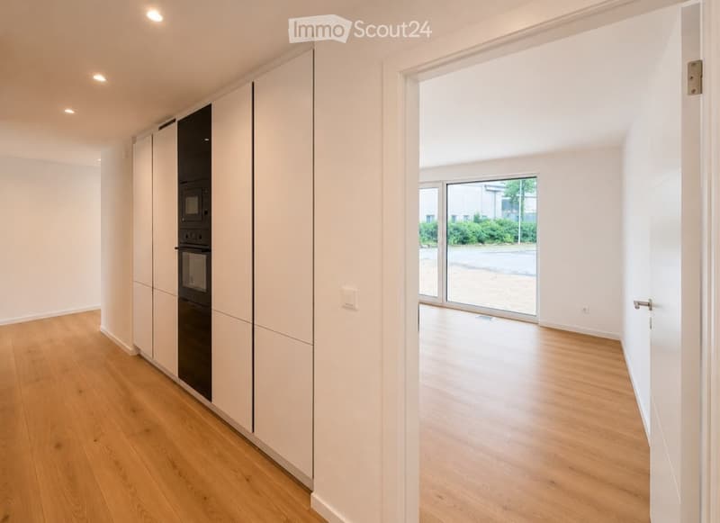Empty room with light wooden flooring, white walls, and built-in cabinets. A large sliding glass door leads to an outdoor area.
