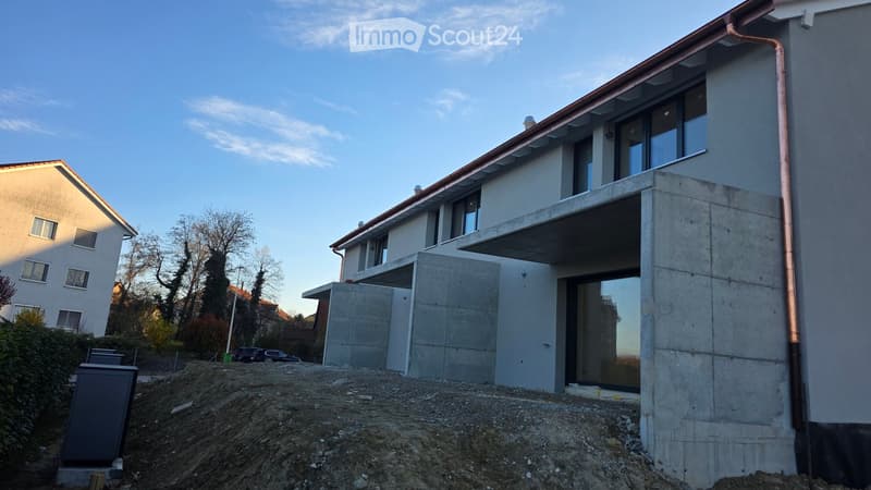 Modern house under construction, concrete walls, large windows, copper gutters, elevated ground floor
