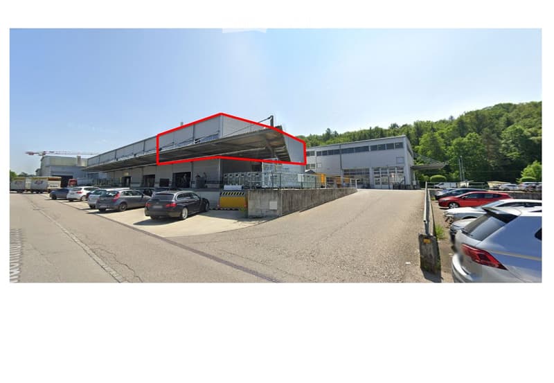 Warehouse building with several parking spaces in front and multiple trucks parked at the side