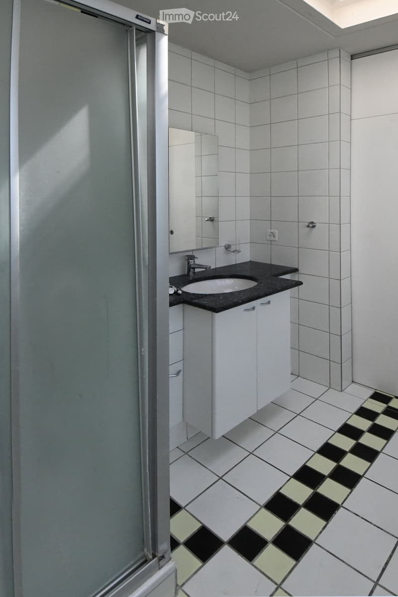 modern bathroom, white tiled walls, checkered tile flooring, glass door, vanity with sink and mirror, chrome faucet