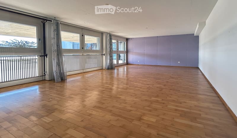 empty room with hardwood floors, large windows, balcony, glass doors, white and purple walls