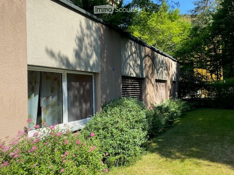 Exterior of the building with windows, shrubs, flowers, and a grassy lawn