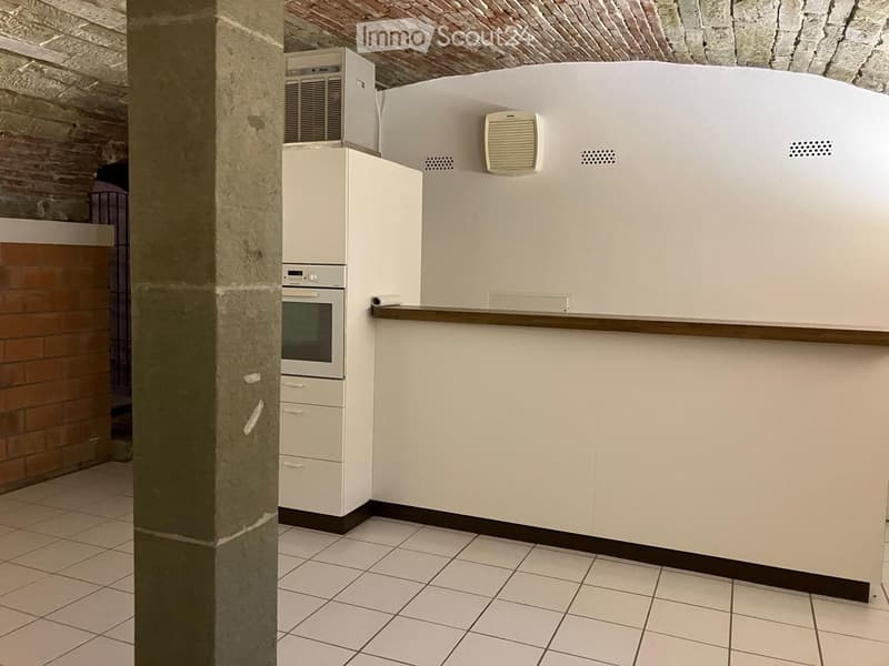 Small kitchen with white tiled floor, white cabinets, white wall, a small oven, and an air conditioning unit.
