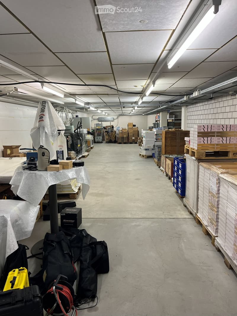 warehouse, gray flooring, long corridor with items, white ceiling, multiple lighting