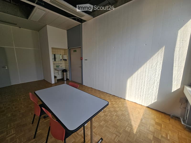white walls, hardwood floor, table with chairs, trash bin, bathroom with sink and mirror