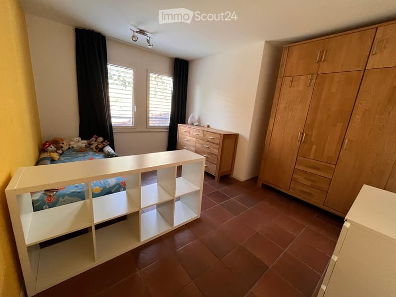bedroom with bed, drawers, shelf, wooden floor, yellow wall