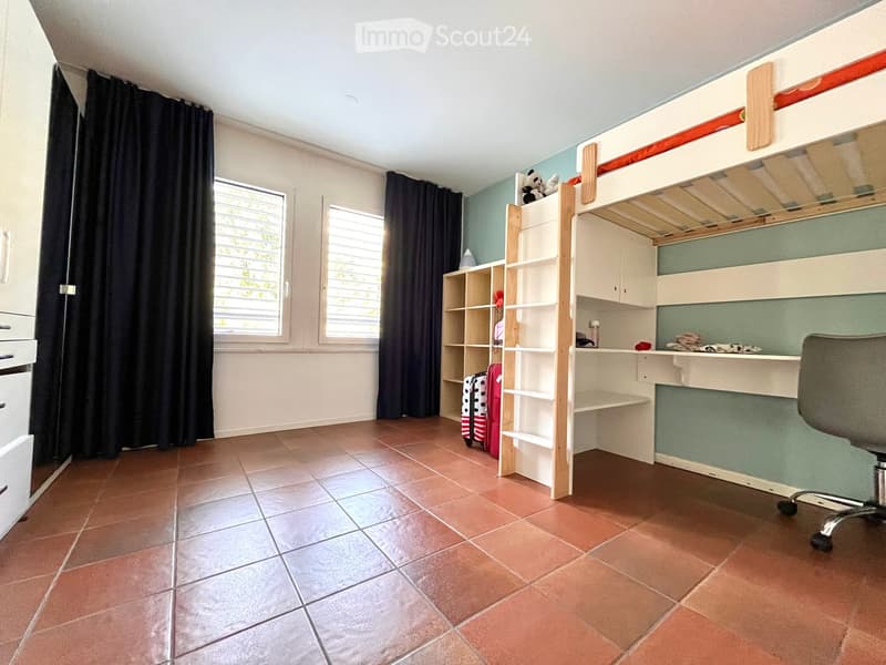 room with red tiles, bunk bed, office chair, wardrobe, window with curtains, shelves, and luggage