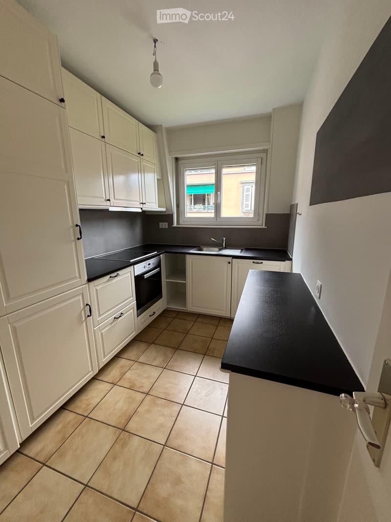 white cabinetry, black countertop, gas stove, oven, sink, window