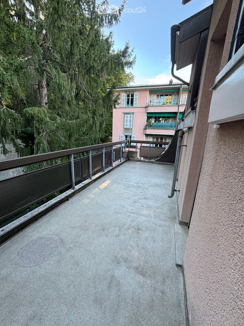 An empty balcony with metal railings and a concrete floor
