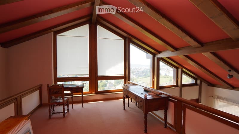 room with sloping ceiling, wooden desk, wooden chair, wooden window sill, window with blinds, carpet floor