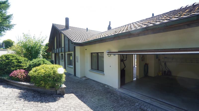 2 story house, beige, open garage, plants, gravel driveway