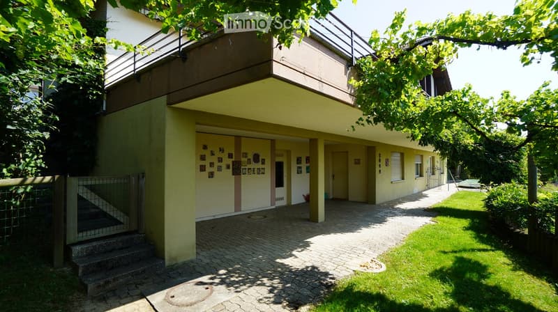 Yellow house with two floors, balcony on top floor, attached garage