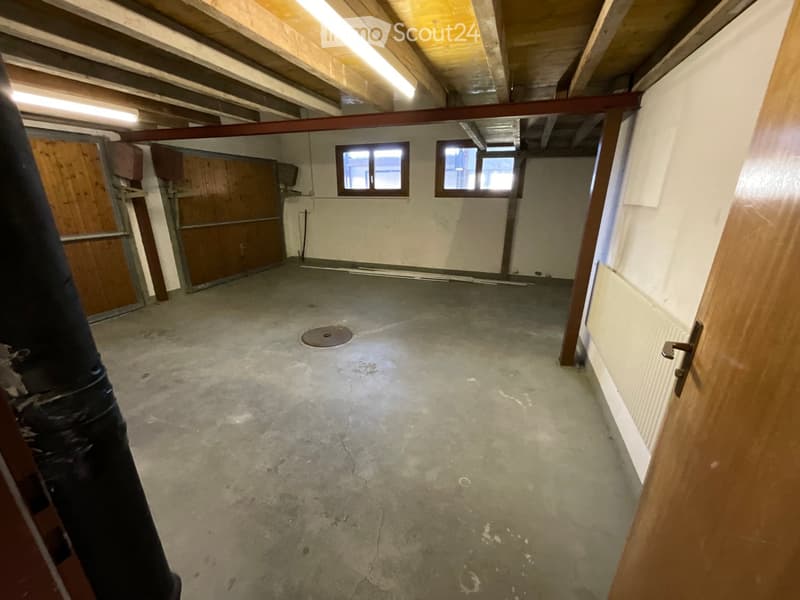 concrete floor, two windows, wooden doors, small floor hole, concrete pillar