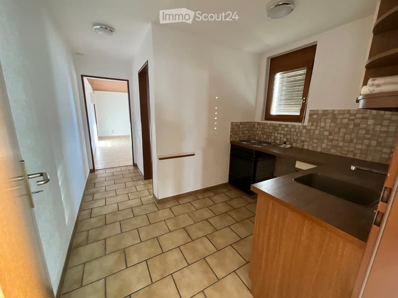 Empty room with a tiled floor, a sink, a countertop, a window, and a stove on the wall.