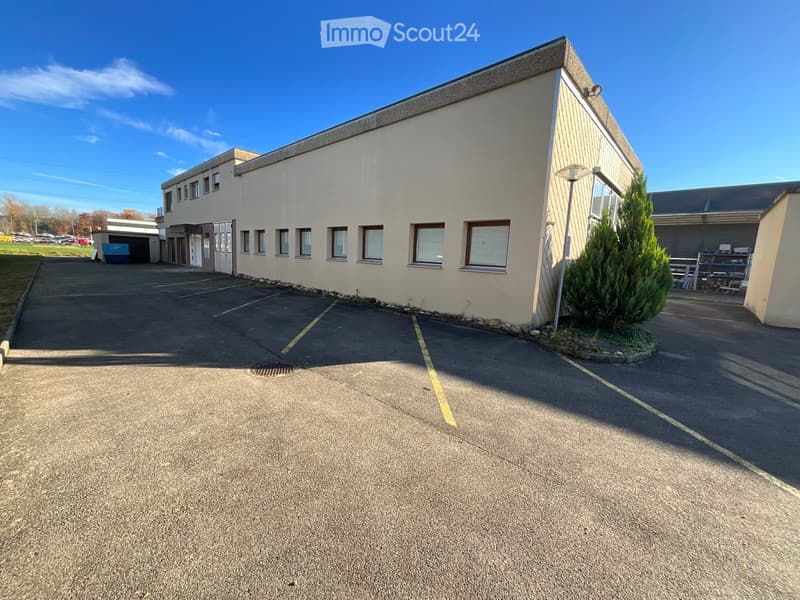 Industrial building, concrete structure, several windows, entrance door, parking area