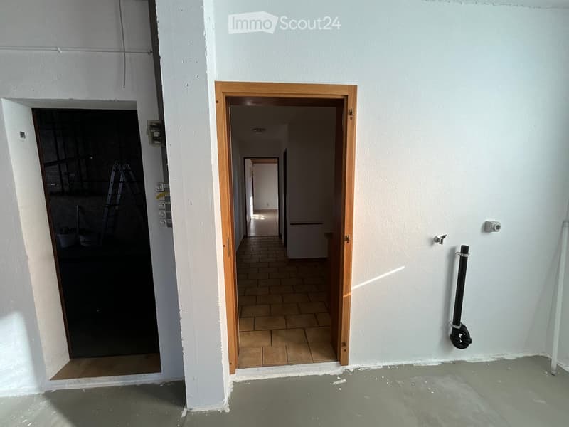 Two rooms in a hallway, one with dark interior and other with open tiled floor