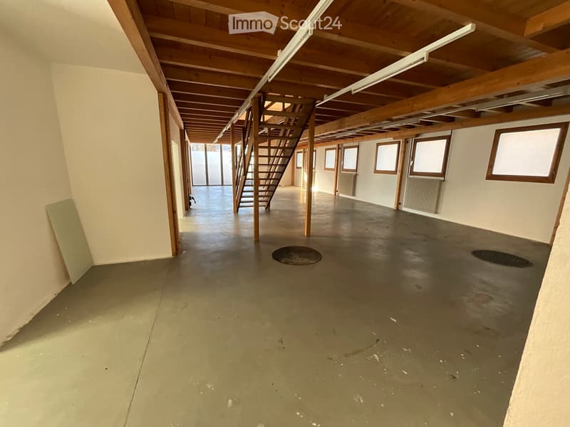 spacious empty room with stairs, exposed wooden beams, windows, radiators