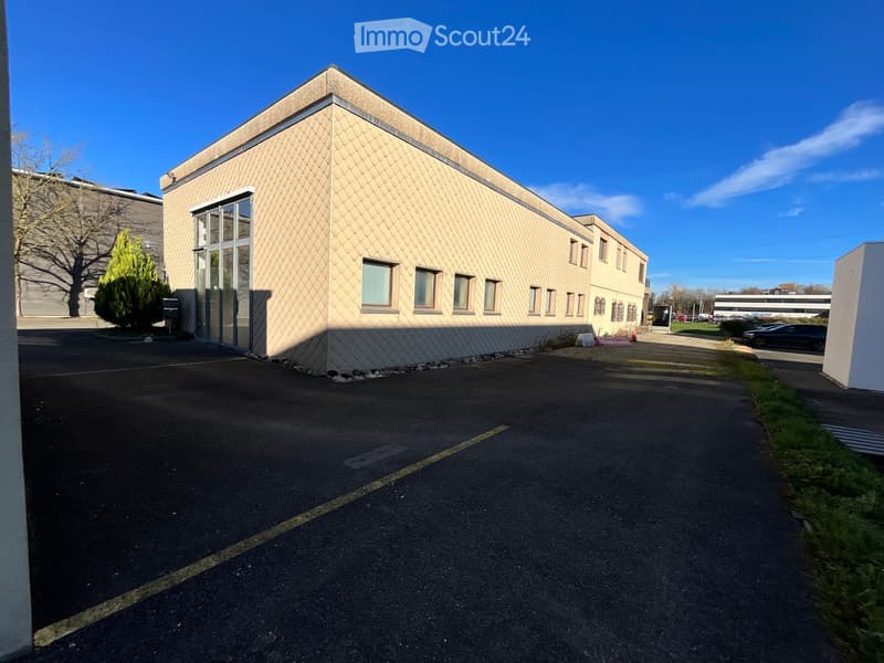 Commercial building with glass windows, beige tiles, and parking lot.