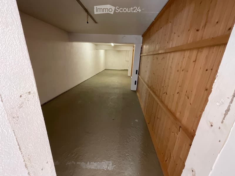 Empty corridor, concrete floor, wooden wall, empty rooms on both sides, small door on the right