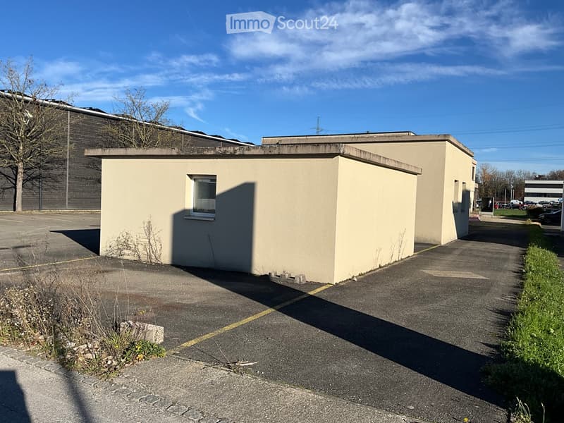 Single-story building, concrete walls, single window, adjacent parking lot