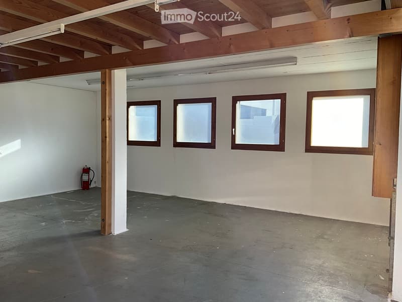 Empty room, wooden ceiling, fire extinguisher on the wall, concrete floor, white walls, three windows.