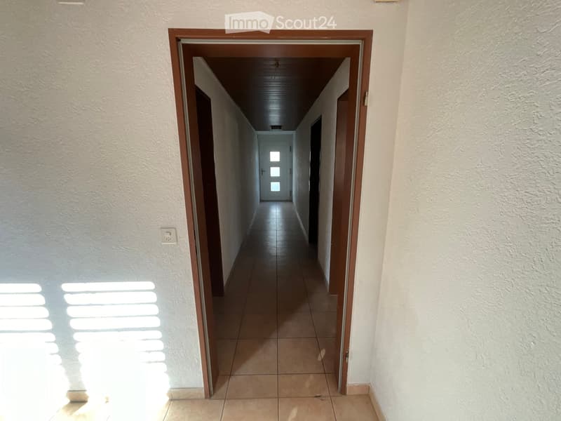 Empty corridor, wooden doors, tiled floor, light coming from end