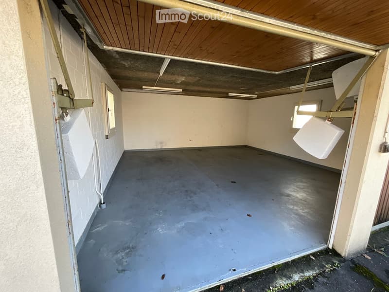 empty garage, concrete floor, wooden ceiling, two windows, no interior fixtures