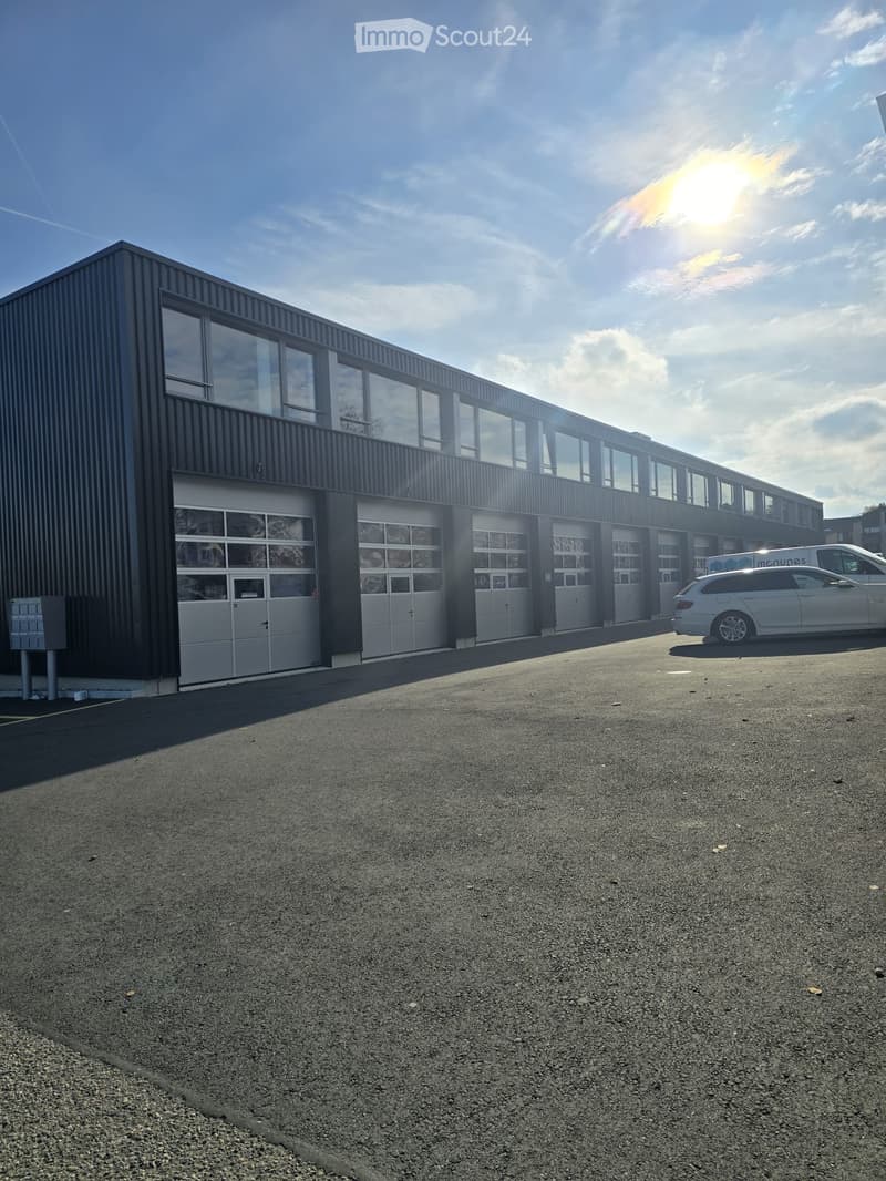 Industrial building with several garage doors, windows, parking space