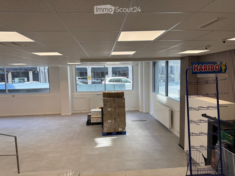 empty room, white walls, large windows, tiled floor, stack of boxes, radiators, surveillance cameras