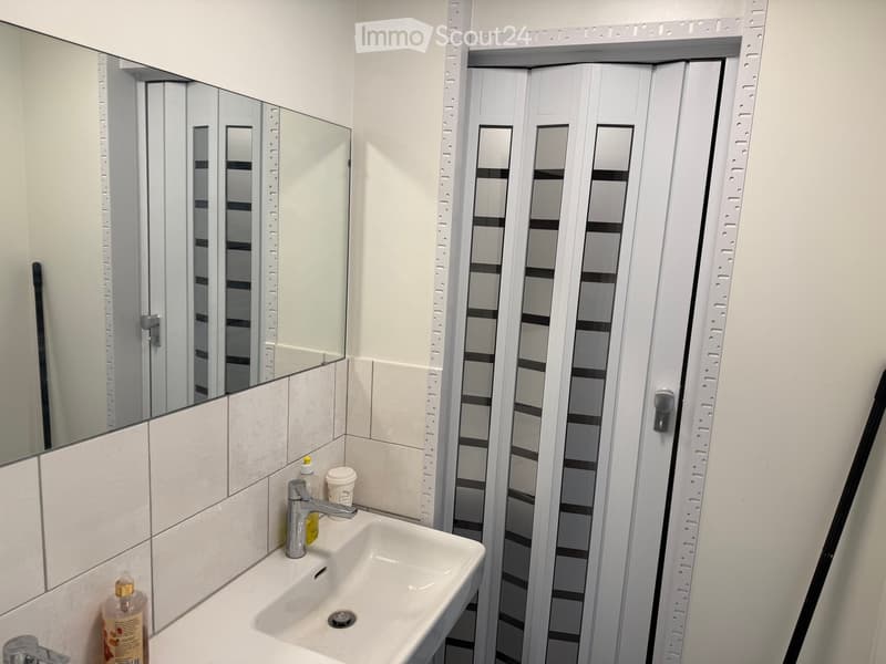 Bathroom with white sink, mirror, and tiled walls