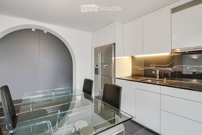 Modern kitchen with a glass table, black chairs, white cabinets, stainless steel refrigerator, and an integrated dishwasher