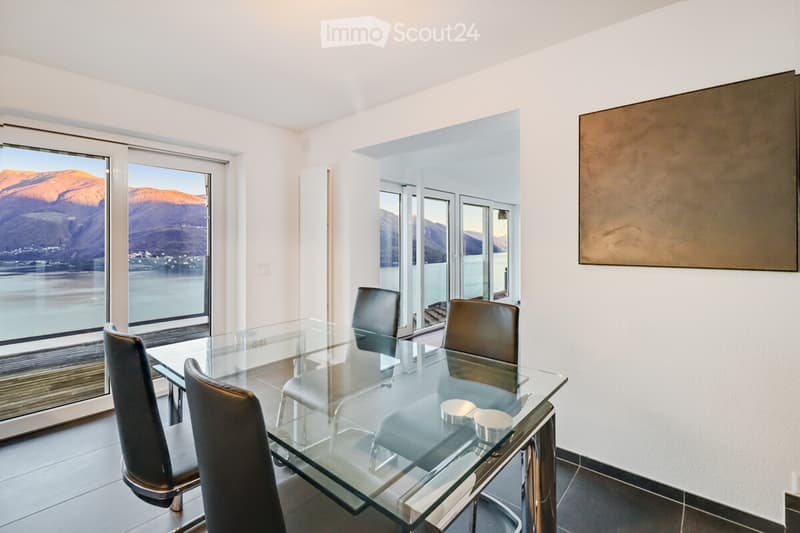 glass table, 4 black chairs, large windows with a view of the mountains and water