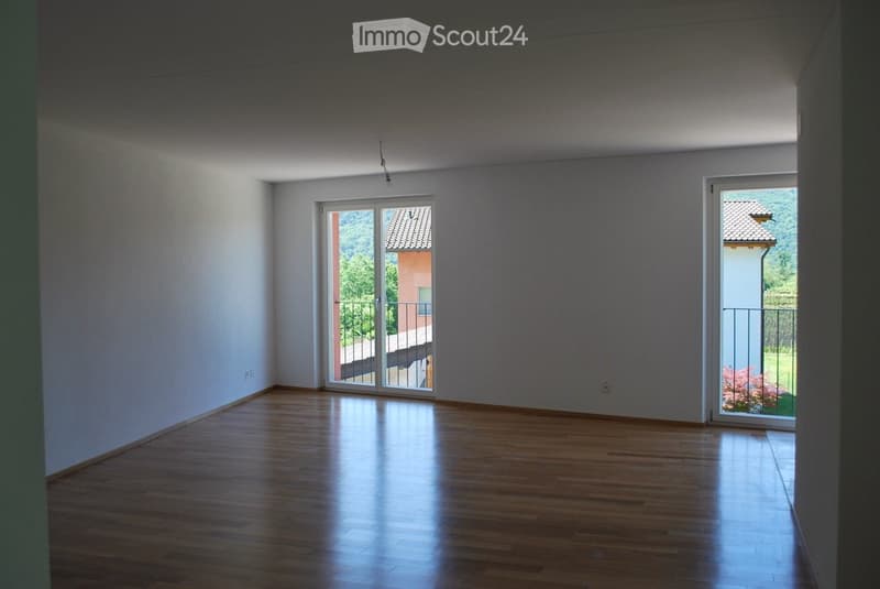 Empty room, wooden floor, sliding glass doors leading to a balcony, white walls, power outlets