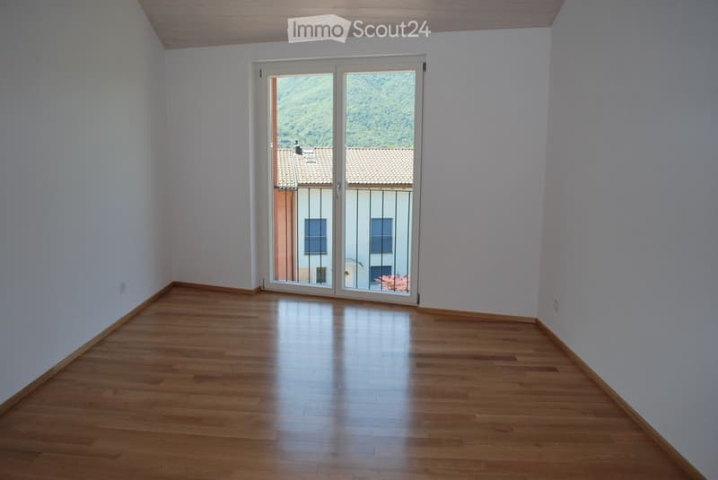 white walls, wooden floor, large glass sliding doors leading to balcony with a view