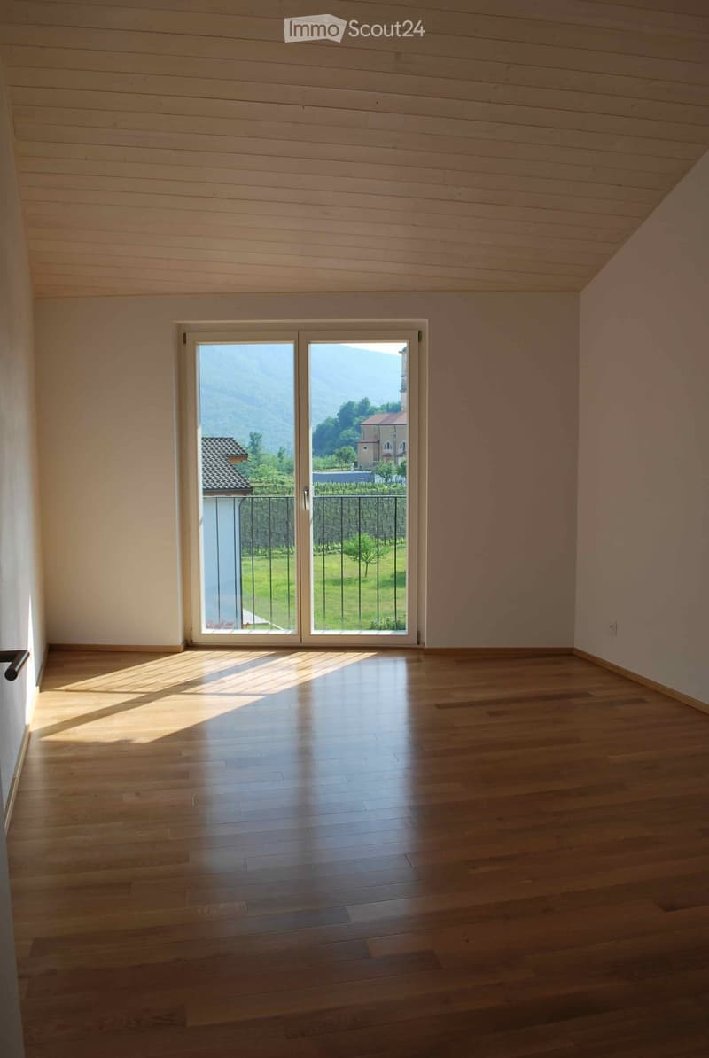 Empty room with wooden floors, white walls, a sliding glass door to a balcony, and a white ceiling